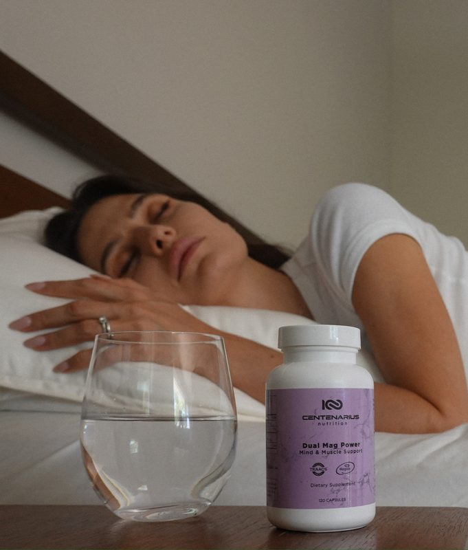 Woman sleeping with Dual Mag Power magnesium supplement on nightstand by Centenarius Nutrition